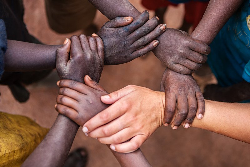 Hands of people from different backgrounds joined together in a circle