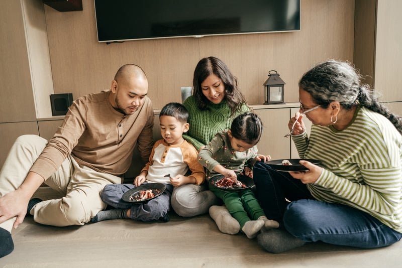 A multi-generational family sitting together sharing a meal at home