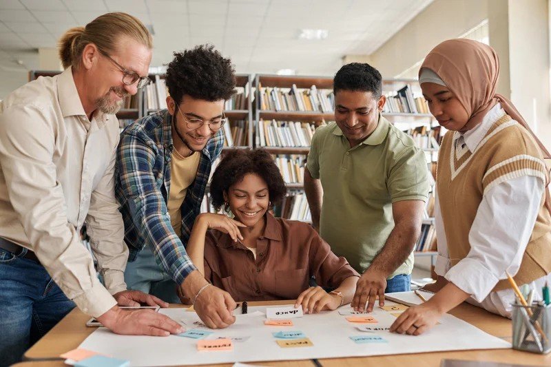 A diverse group of adult ESL students working on English materials around a table