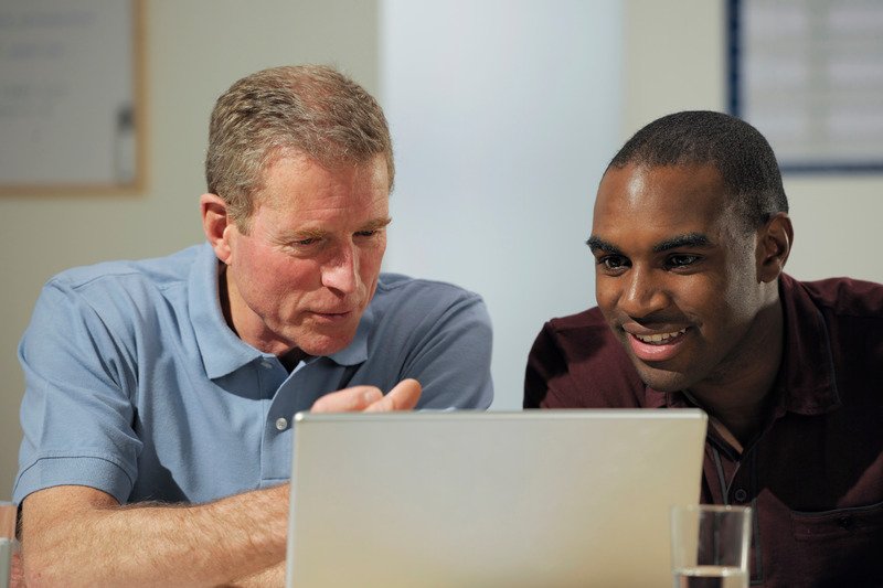 An ESL tutor and student working together at a laptop